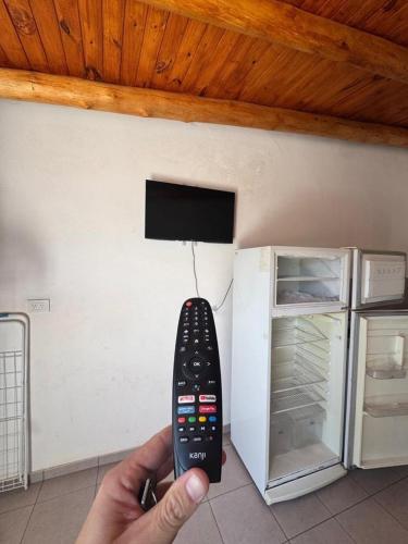 a person holding a remote control in front of a refrigerator at Condominio Atuel con Cocina Wifi Cochera Desayuno in San Rafael