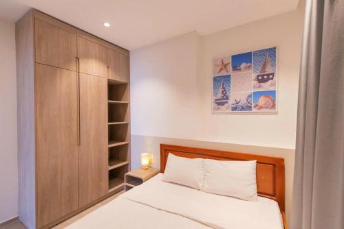 a bedroom with a bed and a wooden cabinet at Sóng Homestay-The Sóng Apartment Vũng Tàu Nghỉ Dưỡng Biển Cao Cấp 5 Sao- The Song Vung Tau Condotel 5 Star Beach View Apartment in Vung Tau