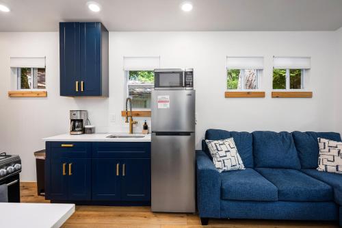 a kitchen with a refrigerator and a blue couch at Beach l Hot Tub l Arbutus Lake l 15 min to DT TC in Traverse City