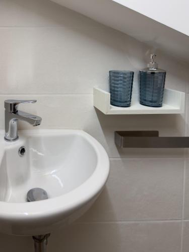 a bathroom with a sink and two blue glasses on shelves at Albachiara House in Calatabiano