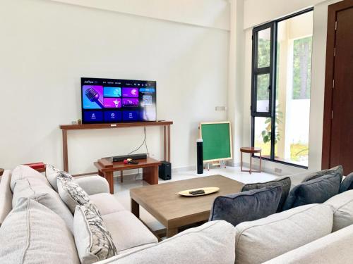 Deco Home The Summit Mesilau at Kundasang في Kampong Kundassan: غرفة معيشة مع أريكة وتلفزيون بشاشة مسطحة