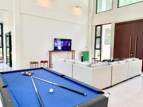 Deco Home The Summit Mesilau at Kundasang في Kampong Kundassan: طاولة بلياردو في غرفة المعيشة مع الأرائك