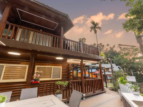 a house with a balcony and a table and chairs at 郭媽媽包棟小木屋民宿 in Gukeng