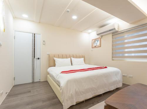 a bedroom with a white bed with a red blanket at 郭媽媽包棟小木屋民宿 in Gukeng