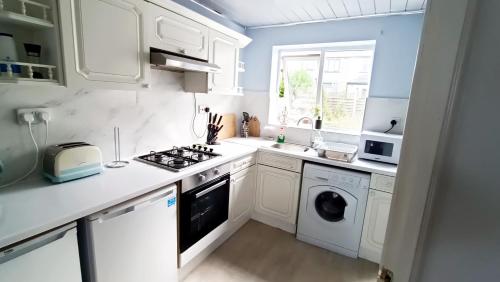 a kitchen with white cabinets and a washer and dryer at Family friendly 3-bed home free parking on site in Huddersfield