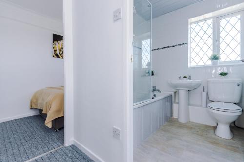 a white bathroom with a toilet and a sink at Family friendly 3-bed home free parking on site in Huddersfield