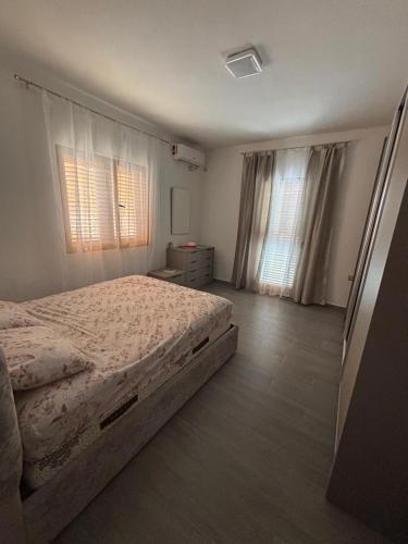 a bedroom with a bed and two windows at Albert's house for rent in Vlorë