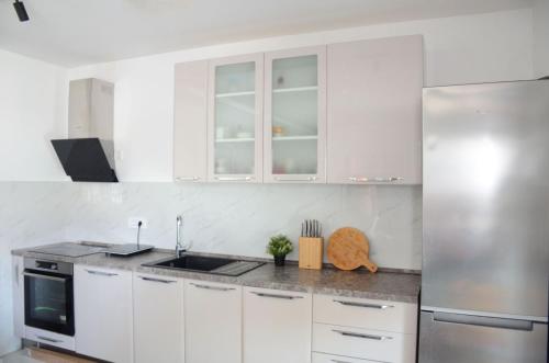 a kitchen with white cabinets and a stainless steel refrigerator at Villa Marbella in Ledine