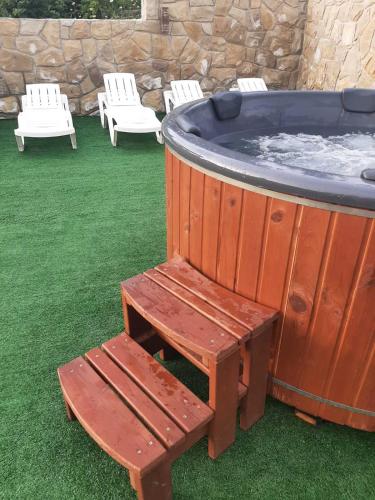 a wooden hot tub with a bench and chairs at У Павла in Yablunytsya