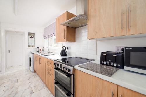 a kitchen with wooden cabinets and a stove top oven at Cooper stay - perfect for contractors in Grimsby