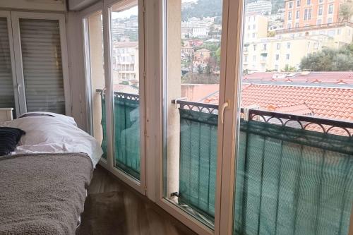 Cette chambre dispose de deux fenêtres et d'un lit sur un balcon. dans l'établissement Charming T2 with Wifi near city center, à Nice