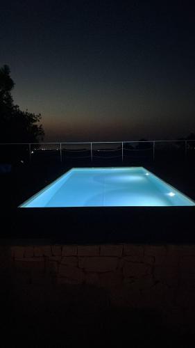 a large blue swimming pool lit up at night at MAREULIVI in Ostuni