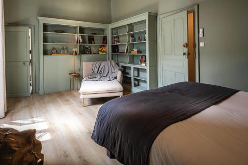 a bedroom with a bed and a chair and shelves at La Chapelle sur la Sorgue in LʼIsle-sur-la-Sorgue