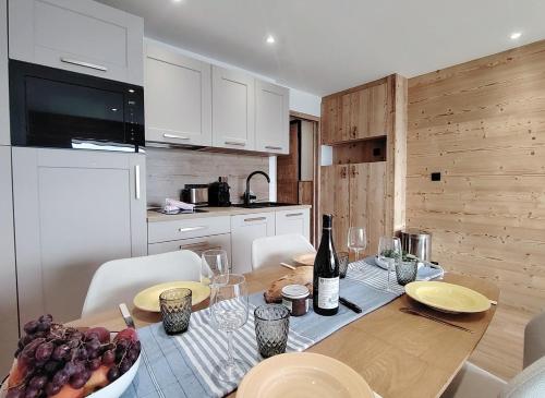 - une cuisine avec une table en bois et une bouteille de vin dans l'établissement Homency - Résidence le Majestic K5, à L'Alpe-d'Huez
