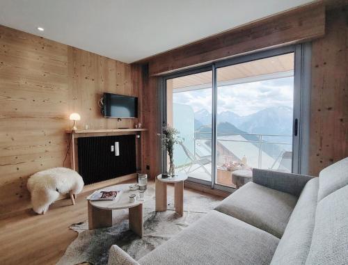 un salon avec un canapé et une grande fenêtre dans l'établissement Homency - Résidence le Majestic K5, à L'Alpe-d'Huez