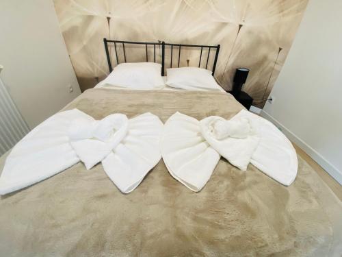 a bed with two white towels with bows on it at Le Saphir Zénith 1 in Amiens