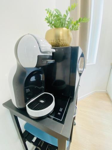 a coffee maker on a table with a plant at Le Saphir Zénith 1 in Amiens
