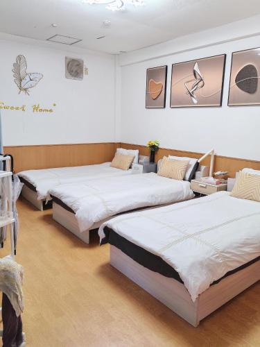 a room with three beds and paintings on the wall at Momo House Near Komagome easy to shinjuku, Ueno, Tokyo in Tokyo
