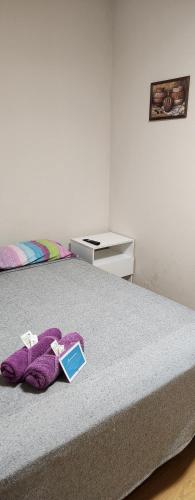 a bed with a purple blanket and a book on it at Hotel Gutierrez in Mendoza