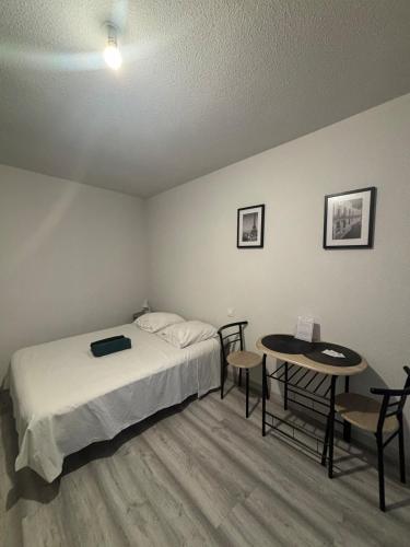 une chambre avec un lit, une table et des chaises dans l'établissement Studio centre ville proche gare, à Roanne