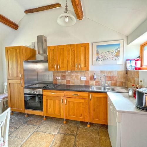 a kitchen with wooden cabinets and a stainless steel appliance at Whitley Coach House in Whitley