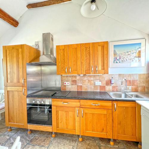a kitchen with wooden cabinets and a sink at Whitley Coach House in Whitley