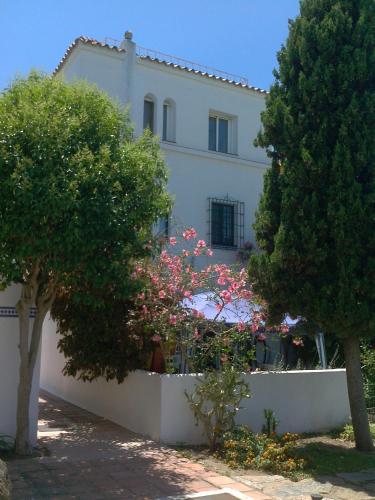 a white house with trees and flowers in front of it at Rio Manilva in San Luis de Sabinillas