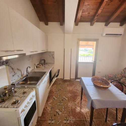 a kitchen with a stove and a sink and a table at REZIDENCA ARBNORE - Tre Horizonte in Koplik