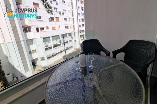 a glass table with wine glasses on it in front of a window at Tropical Paradise 200m from Finikoudes beach in Larnaca