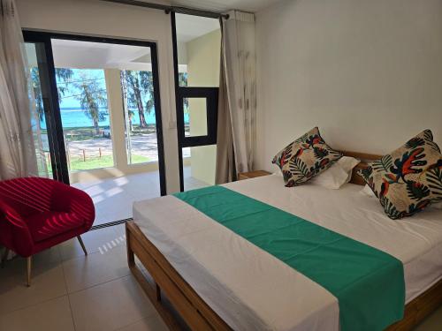 a bedroom with a bed and a chair and a window at Ayami Bay in Flic-en-Flac