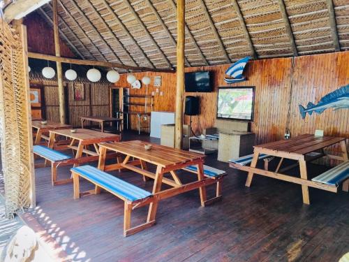 a room with wooden tables and benches and a television at Viva O Sonho 