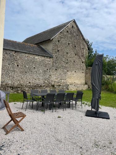 a table with chairs and an umbrella in front of a building at Chez Nana in Russy
