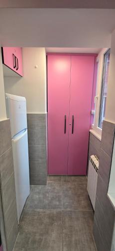 a pink door in a room with a refrigerator at Lux Apartman Stojanović in Belgrade