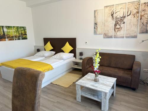 ein Schlafzimmer mit einem Bett, einer Couch und einem Tisch in der Unterkunft Ferienwohnung Thermenauszeit - mit Balkon und Bademantelgang in Bad Griesbach