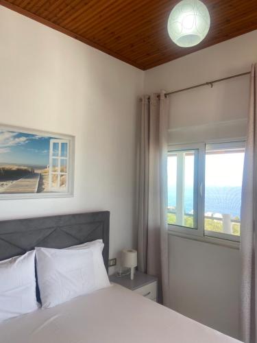 a bedroom with a white bed and a window at Yard Paradise in Dhërmi