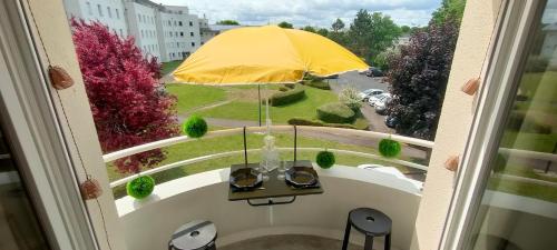 a balcony with a table and a yellow umbrella at Appartement Le doux Viking, balcon & parking privé proche Zénith Caen in Caen