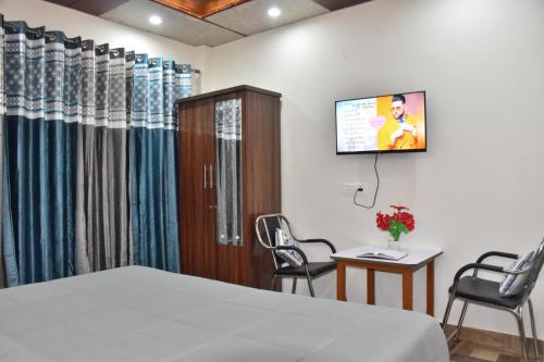 a hospital room with a bed and a tv on the wall at A Greenwoods Hotel in Solan