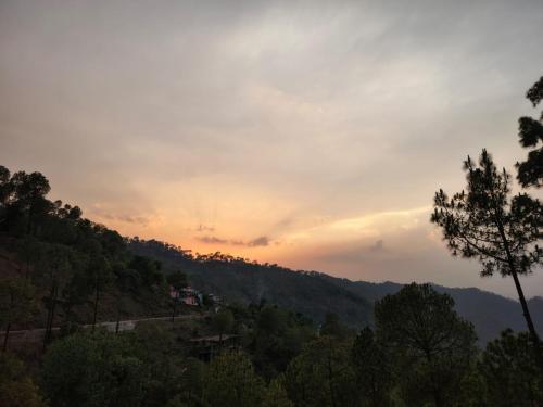 a view of a mountain with a sunset in the background at A Greenwoods Hotel in Solan