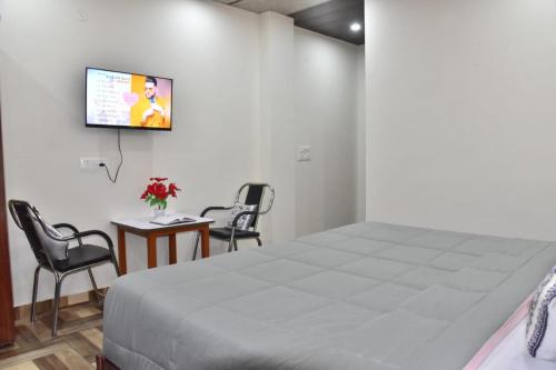 a bedroom with a bed and two chairs and a tv at A Greenwoods Hotel in Solan