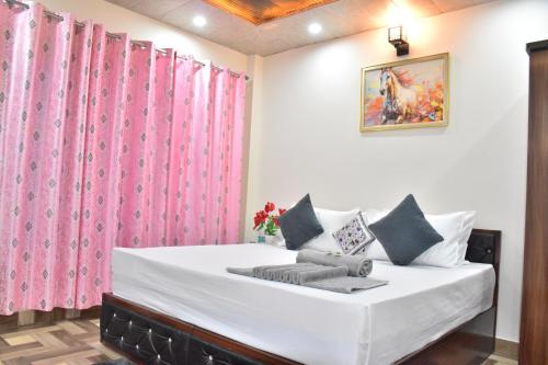 a bedroom with a large white bed with pink curtains at The Blissful Escapes !!! in Dharampur