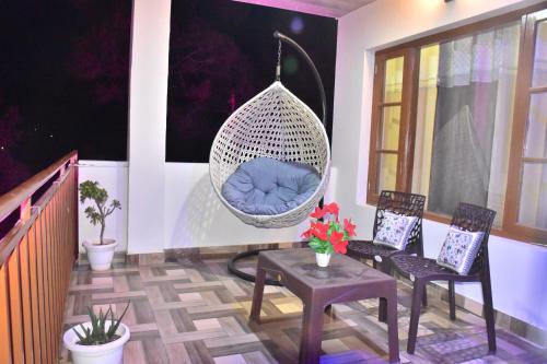 a porch with two chairs and a hanging swing at The Blissful Escapes !!! in Dharampur