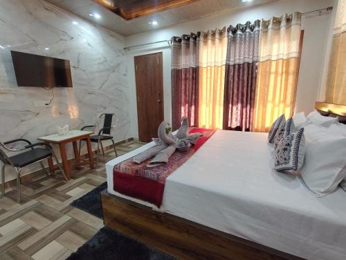a bedroom with a large bed and a table and chairs at A Greenwoods Hotel in Solan