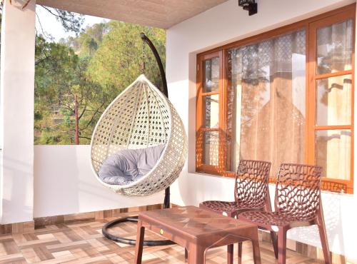 a hanging hammock in a room with two chairs and a table at A Greenwoods Hotel in Solan