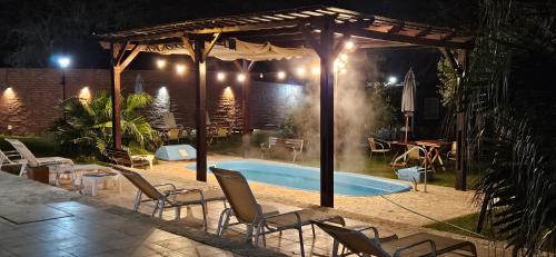 a swimming pool with chairs and a pavilion at night at EL CHALET in Termas de Río Hondo