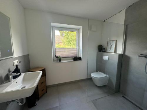 HemmingstedtにあるFerienwohnung Verdeの洗面台、トイレ、窓のあるバスルーム