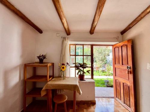 a room with a table with a vase of flowers at La Huerta Refugio in Urubamba