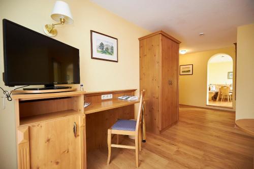 a living room with a tv and a desk with a television at Gasthof-Hotel Zur Post Samerberg in Törwang