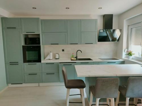 a kitchen with green cabinets and a counter with chairs at Apartman Fortis in Knin