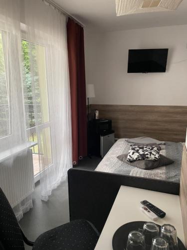 a room with a bed and a table and a television at Antonina ***PensjonPrzyKortach*** in Szczawno-Zdrój