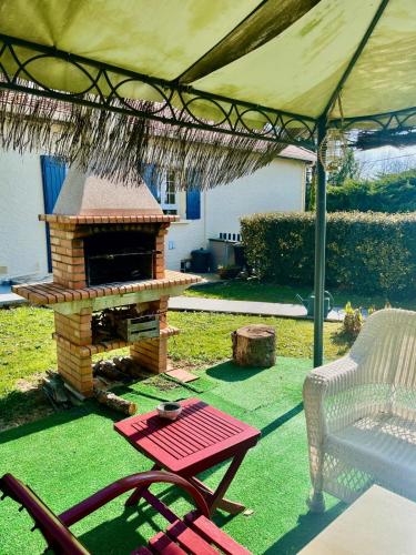 une terrasse avec un grill, une table et une chaise dans l'établissement Splendide Villa et Studio Climatisés-Grande Piscine-Vaste Parc, à Saint-Sauveur